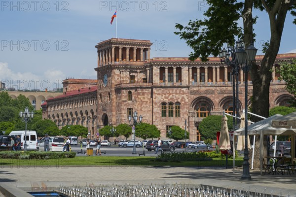 An impressive historic stone building with colonnades, surrounded by people and cars in an urban environment, Government Palace on Republic Square, Yerevan, Yerevan, Armenia
