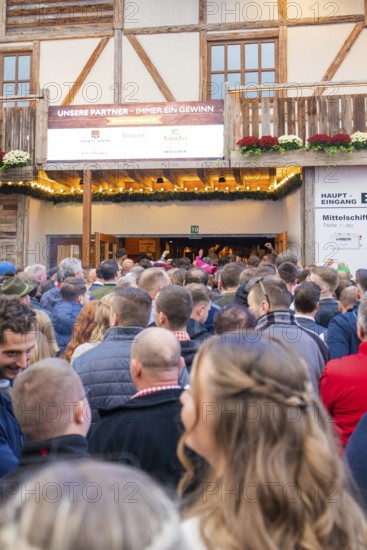 Crowds of people standing in front of the entrance to a wooden building, expectant atmosphere, Cannstatter Wasen fair, Stuttgart, Germany