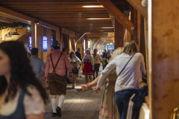 People in traditional dress walk through a corridor in a venue, Cannstatter Wasen folk festival, Stuttgart, Germany