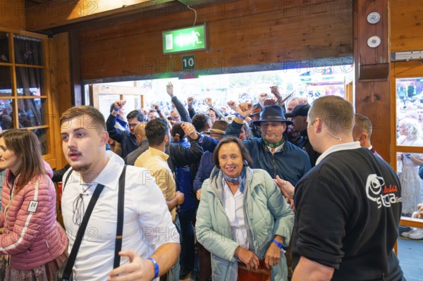 People in traditional traditional costume standing at the entrance to the marquee, lively atmosphere, Cannstatter Wasen folk festival, Stuttgart, Germany
