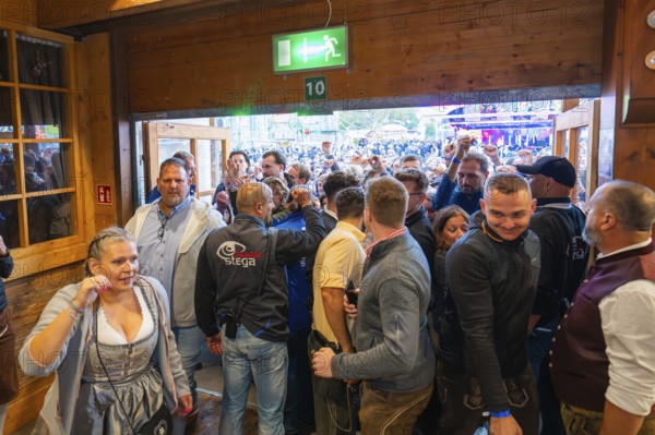 Crowd of people pushing through the entrance of a marquee, lively scene, Cannstatter Wasen folk festival, Stuttgart, Germany