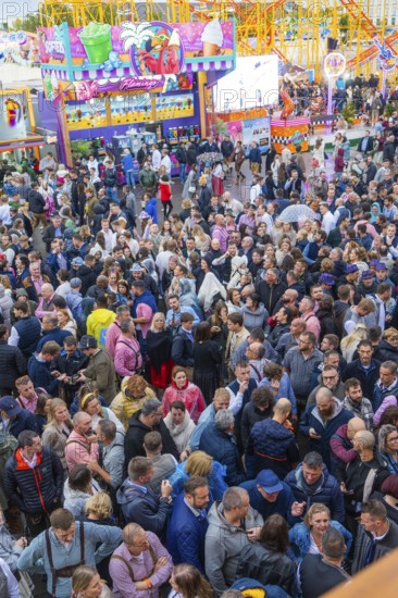 Dense crowd on a busy fairground with colourful lights, Cannstatter Wasen funfair, Stuttgart, Germany