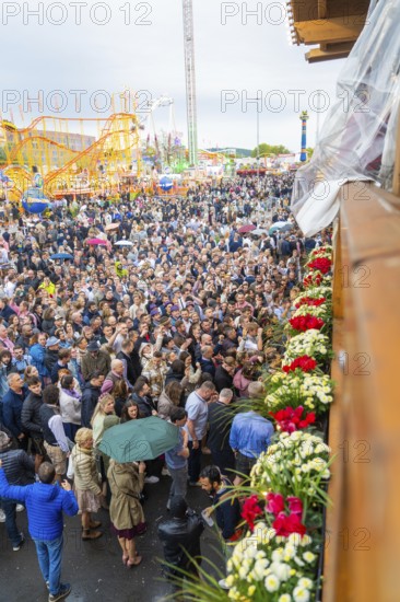Many people at a lively folk festival, colourful flowers in the foreground, Cannstatter Wasen folk festival, Stuttgart, Germany