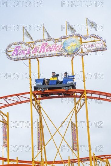 Roller coaster car on rails with rock and roller lettering and colourful flags, Cannstatter Wasen folk festival, Stuttgart, Germany