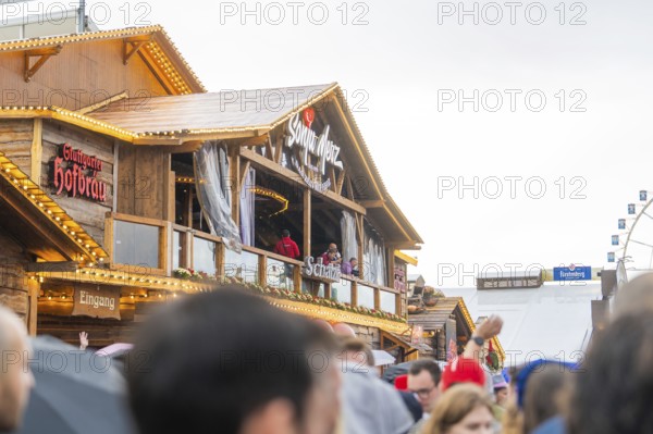 Bavarian wooden building in rainy weather with people in the foreground, Cannstatter Wasen folk festival, Stuttgart, Germany