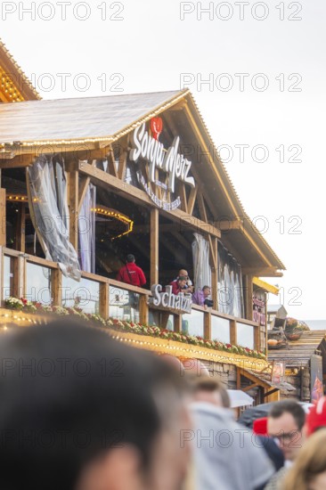 People standing on a balcony of a Bavarian wooden building with a glass front, Cannstatter Wasen folk festival, Stuttgart, Germany
