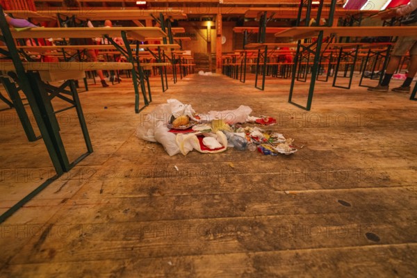 Abandoned interior with wooden benches and rubbish lying on the floor, Cannstatter Wasen folk festival, Stuttgart, Germany