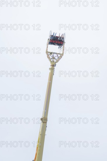 A high ride with people high in the air in front of a blue sky, Cannstatter Wasen folk festival, Stuttgart, Germany