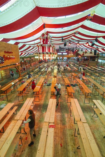 Setting up a marquee with red and white stripes, empty benches and light-coloured wooden floor, Cannstatter Wasen folk festival, Stuttgart, Germany