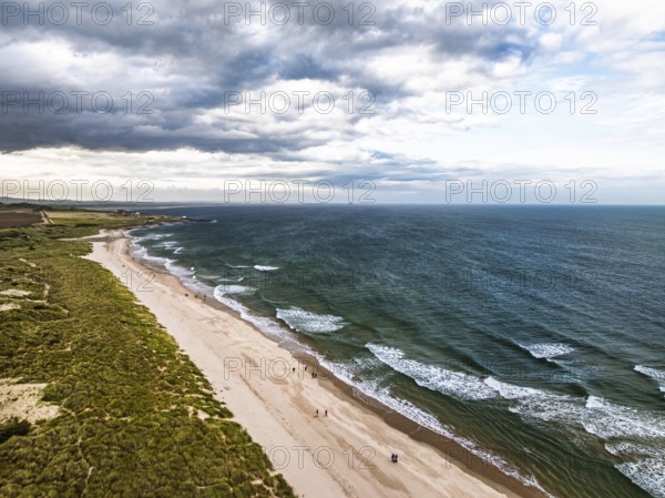 Beach and Dunes over Bamburgh Castle from a drone, Northumberland, Northeast Coast, England, United Kingdom