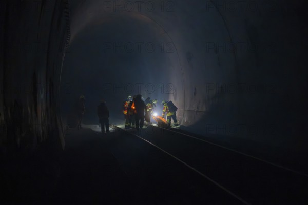 Firefighters at work in a dark tunnel on tracks, firefighting exercise in the new construction tunnel of the Hermann Hesse railway, Ostelsheim, Calw district, Germany