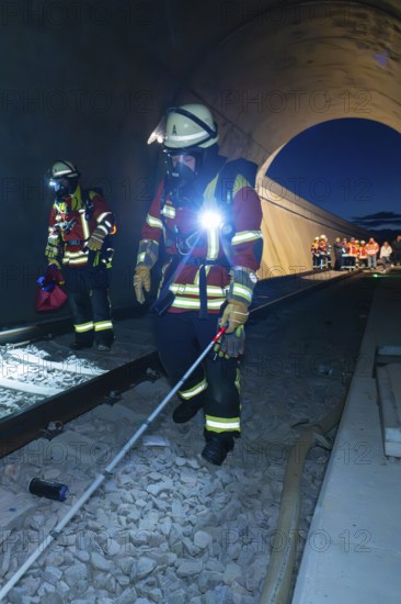 Firefighters with equipment walk along tracks in a tunnel, firefighting exercise in the new tunnel of the Hermann Hessebahn railway, Ostelsheim, Calw district, Germany