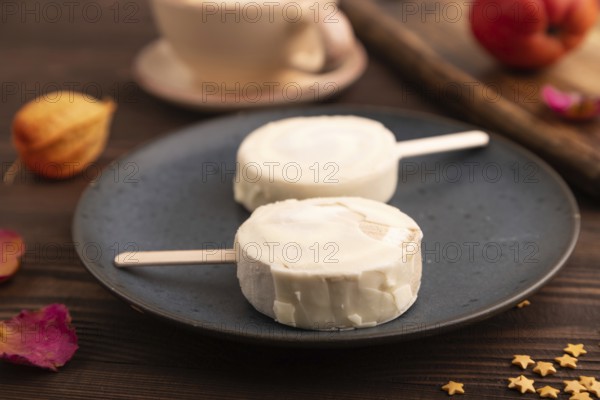 ?hocolate Ice cream in white glaze, cup of coffee, on brown wooden background, side view, close up, selective focus