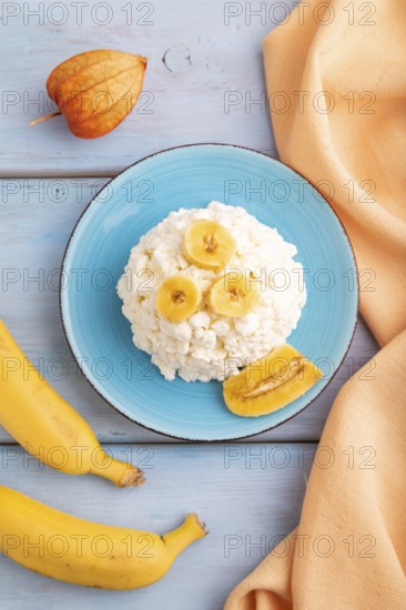 White ?ottage cheese, Curd, with Banana on blue wooden background and orange textile, top view, flat lay, close up
