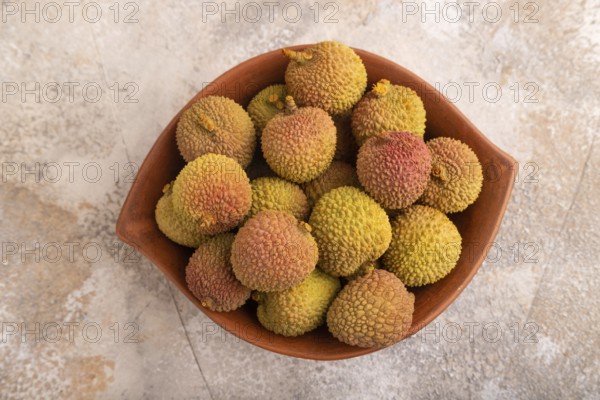 Ripe Lychee on clay bowl on brown concrete background, top view, flat lay, close up, minimalism