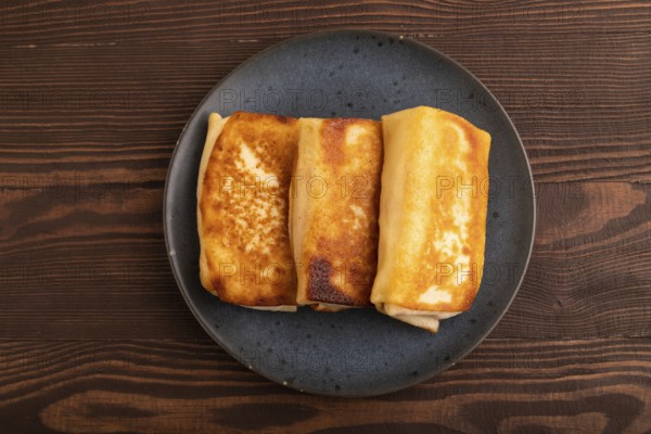 Fried crispy pancakes with meat and cheese on brown wooden background. top view, flat lay, copy space