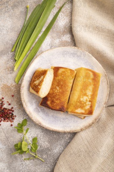 Fried crispy pancakes with meat and cheese on brown concrete background and linen textile. top view, flat lay, close up