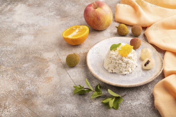 White ?ottage cheese, Curd, with orange and lychee on brown concrete background and orange textile, side view, copy space