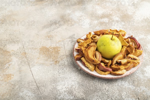 Dried Apples in ceramic bowl on brown concrete background. Side view, copy space, flat lay. healthy food, minimalism. sweet