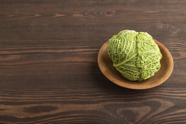 Green lettuce on plate on brown wooden background. Side view, copy space. healthy food, vegetable, minimalism