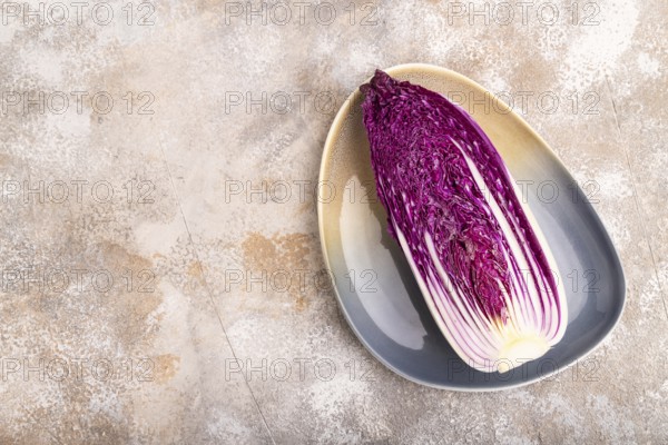 Purple Chinese cabbage on blue plate on brown concrete background, top view, flat lay, copy space, minimalism