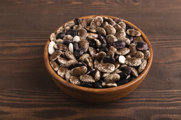 Wooden bowl with Kidney beans on brown wooden background, side view, close up, minimalism
