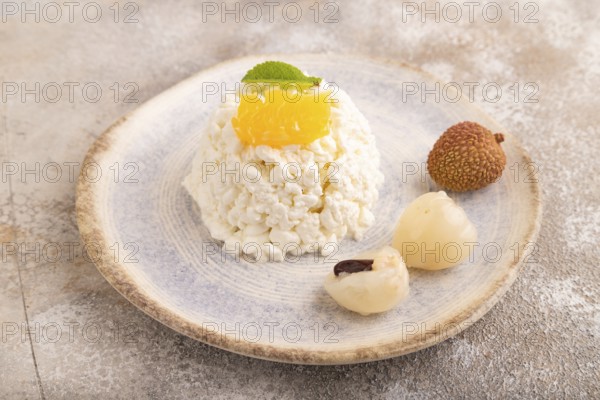 White ?ottage cheese, Curd, with orange and lychee on brown concrete background, side view, close up
