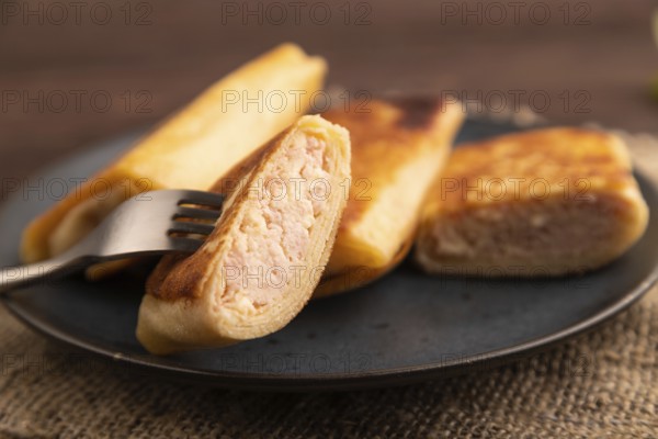 Fried crispy pancakes with meat and cheese on brown wooden background and linen textile. side view, close up, selective focus