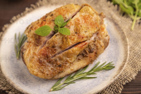 Fried Turkey Thigh with spices and rosemary on plate on brown wooden background and linen textile. side view, close up, selective focus