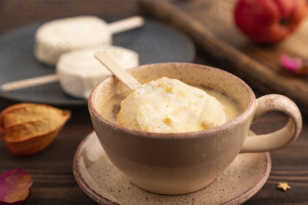 ?hocolate Ice cream in white glaze, cup of coffee, on brown wooden background, side view, close up, selective focus