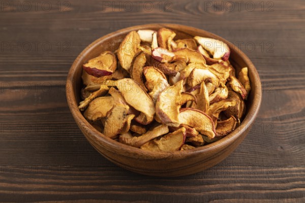 Dried Apples in wooden bowl on brown wooden background. Side view, close up, healthy food, minimalism. sweet
