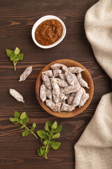 Small smoked Chicken sausages in wooden bowl on brown wooden background and linen textile. top view, flat lay, close up