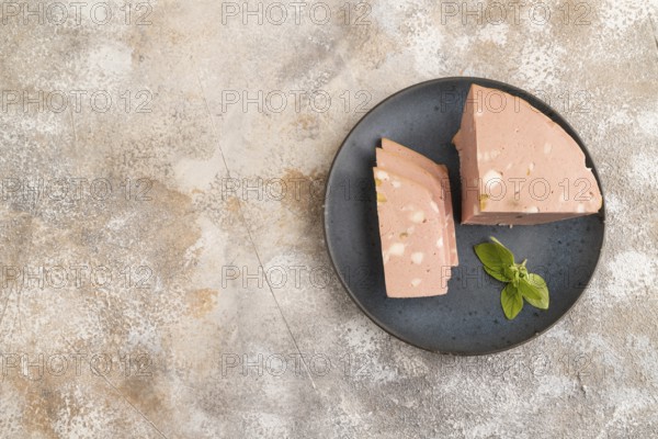 Mortadella sausage on plate with pepper and herbs on brown concrete background. Top view, flat lay, copy space