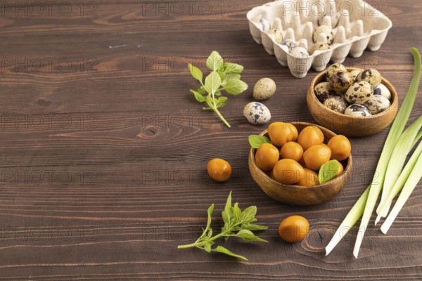 Pile of Smoked Quail eggs in bowl on a brown wooden background. side view, copy space