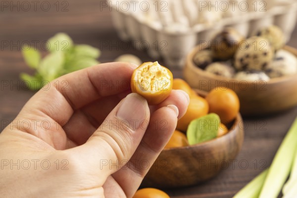 Pile of Smoked Quail eggs in bowl with hand on a brown wooden background. side view, close up, selective focus