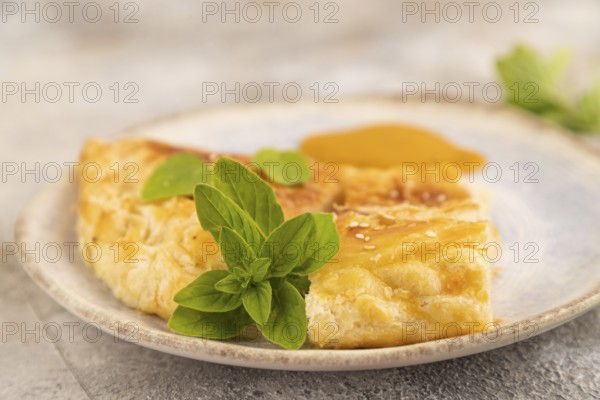 Fried homemade Khachapuri cake with cheese and meat, fried in pan. Traditional Georgian cuisine on brown concrete background. Side view, close up, selective focus