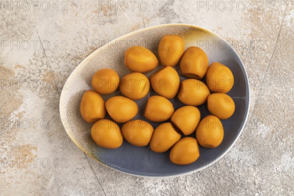 Pile of Smoked Quail eggs on plate on a brown concrete background. top view, flat lay, close up