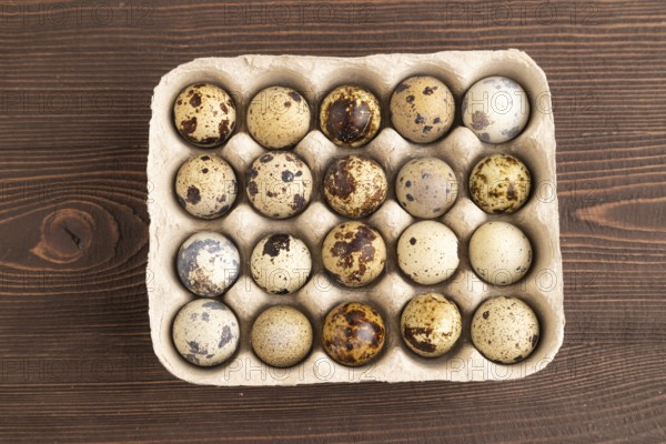 Pile of raw Quail eggs on brown wooden background. top view, flat lay, copy space