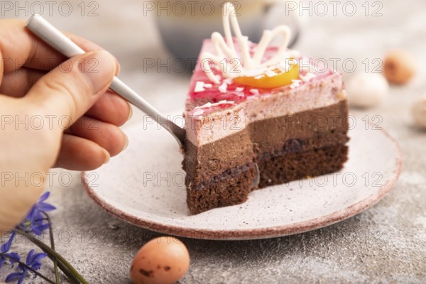 Chocolate cake with hand on brown concrete background, cup of coffee, side view, close up, selective focus