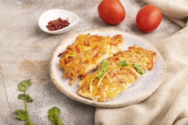 Baked chicken meat with cheese and tomatoes on brown concrete background and linen textile. side view, close up