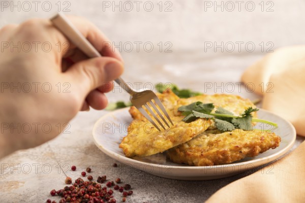 Fried crispy Chicken pancakes on brown concrete background and orange linen textile with hand. side view, close up, selective focus