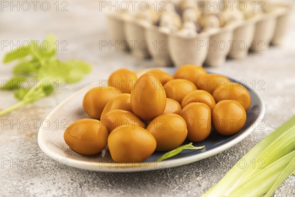 Pile of Smoked Quail eggs on plate on a brown concrete background. side view, close up, selective focus