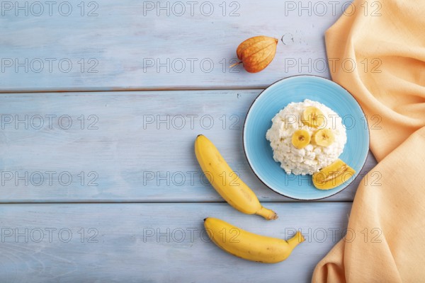 White ?ottage cheese, Curd, with Banana on blue wooden background and orange textile, top view, flat lay, copy space