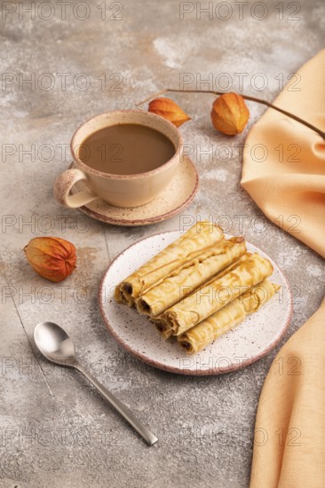 Waffles with caramel on brown concrete background and orange linen textile, cup of coffee, side view, close up