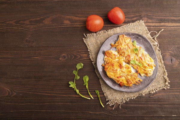 Baked chicken meat with cheese and tomatoes on brown wooden background and linen textile. top view, flat lay, copy space