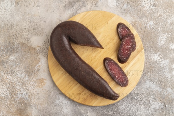 Sujuk sausage on wooden cutting board with pepper and herbs on brown concrete background. Top view, flat lay, copy space