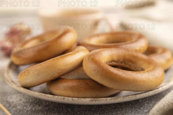 Homemade Ring Bagel with cup of coffee on brown concrete background and linen textile. side view, close up, selective focus