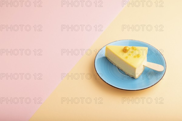 Yellow Cake pop with sprinkles on blue ceramic plate on pink and orange pastel paper background, side view, copy space, minimalism