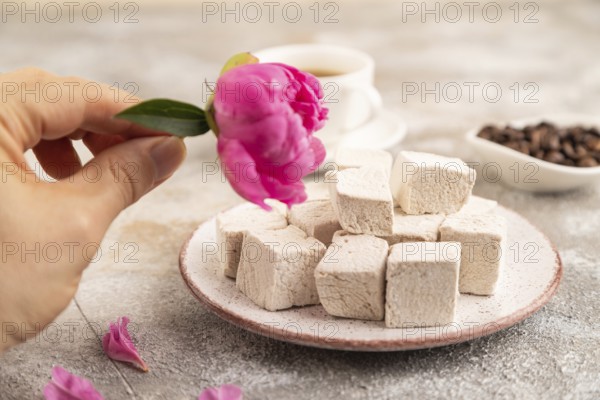 Coffee marshmallow with cup of coffee with hand on brown concrete background. side view, close up, selective focus