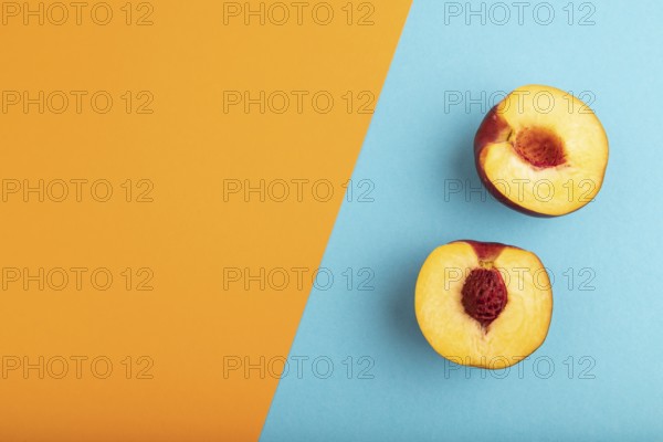 Peach Cut in half on orange and blue paper pastel background. Top view, flat lay, copy space. healthy food, minimalism